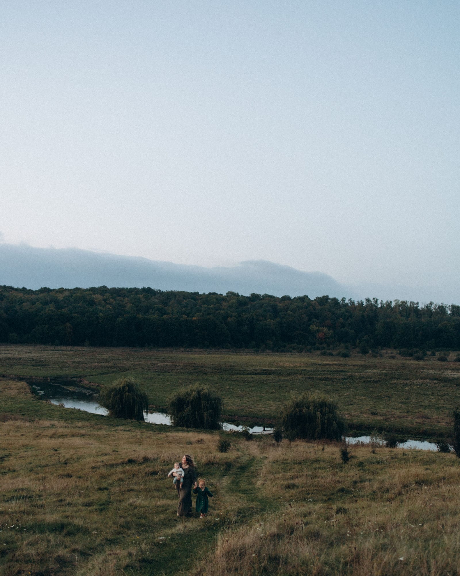 A family walking a trail through open countryside at dusk